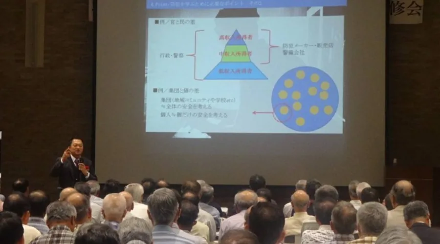 講師が大きなスクリーンを使って防犯について話す様子