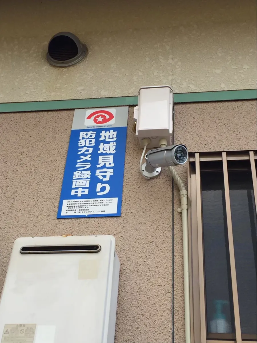 建物の外壁に設置された地域見守りカメラと表示板