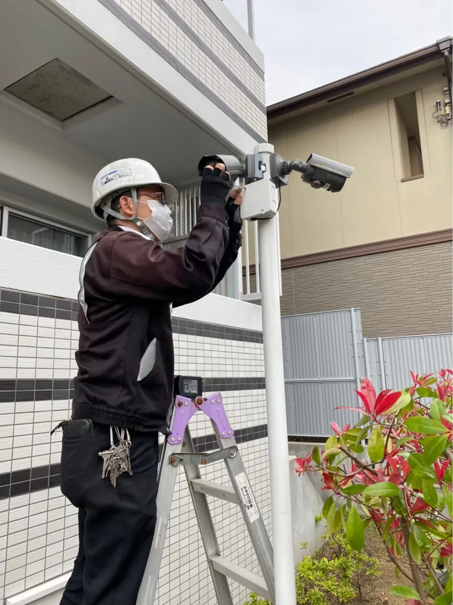 脚立に上り防犯カメラを取り付ける当社スタッフ